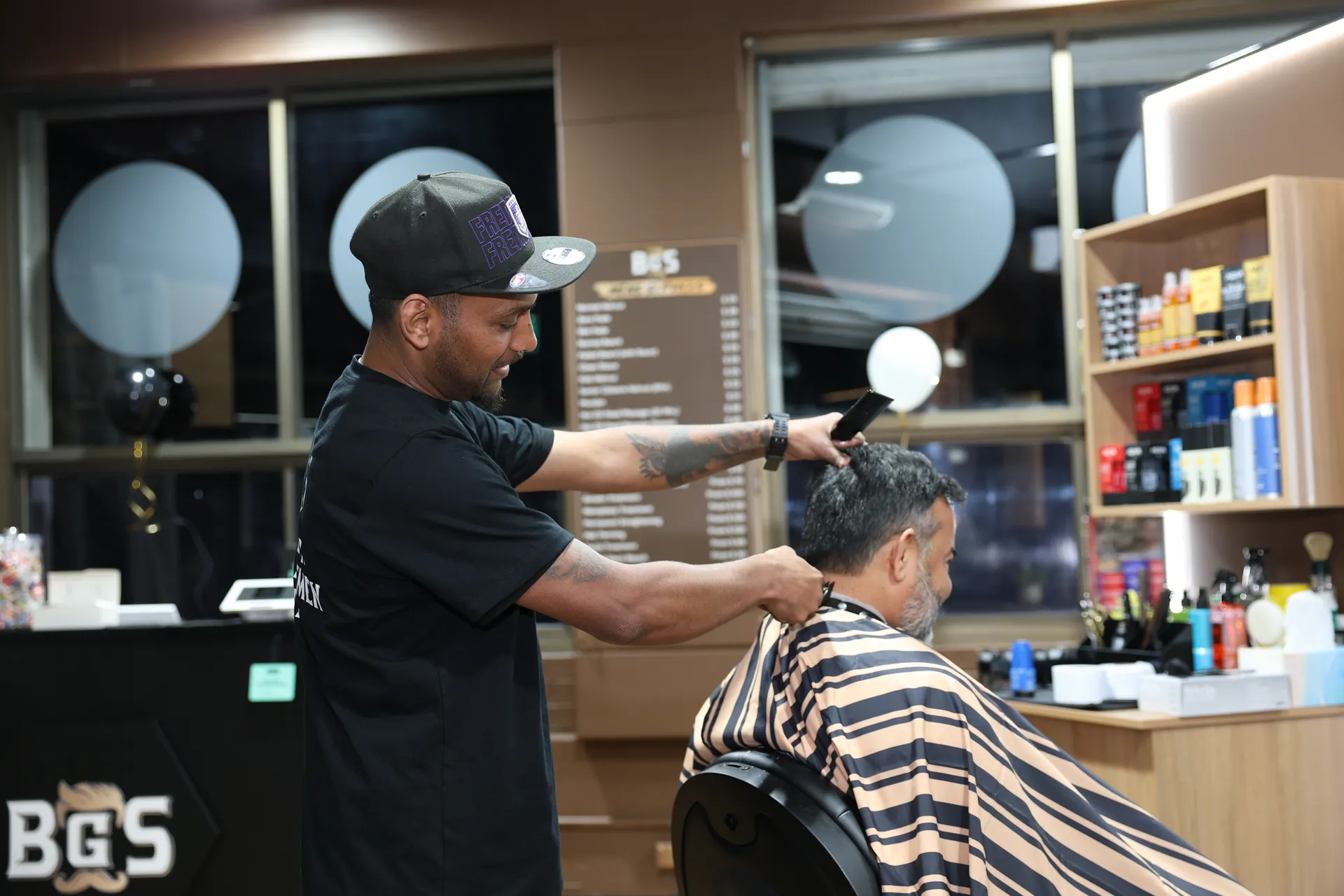 A BGS artist styling a client's hair beside the salon mirror