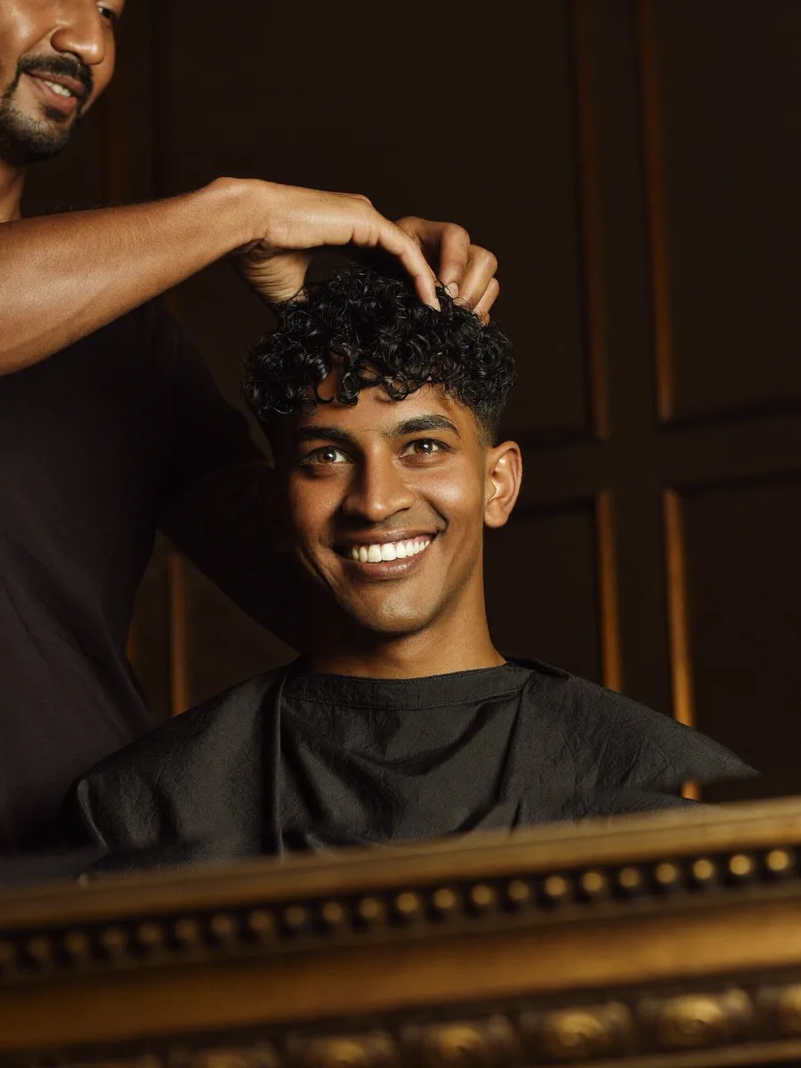 An Indian man smiling at his freshly permed curls